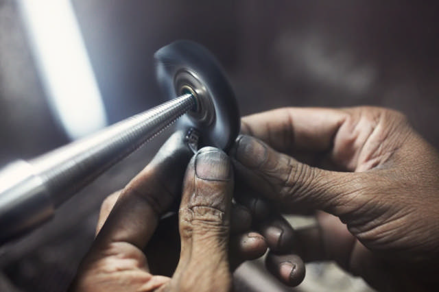 Industrielles Schleifen und Polieren ist bei Röckelein eine Kernleistung. Eine Hand, die gerade etwas für einen Industriekunden schleift wird dargestellt.